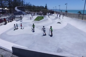 A group of children use scooters and skateboards at a skatepark