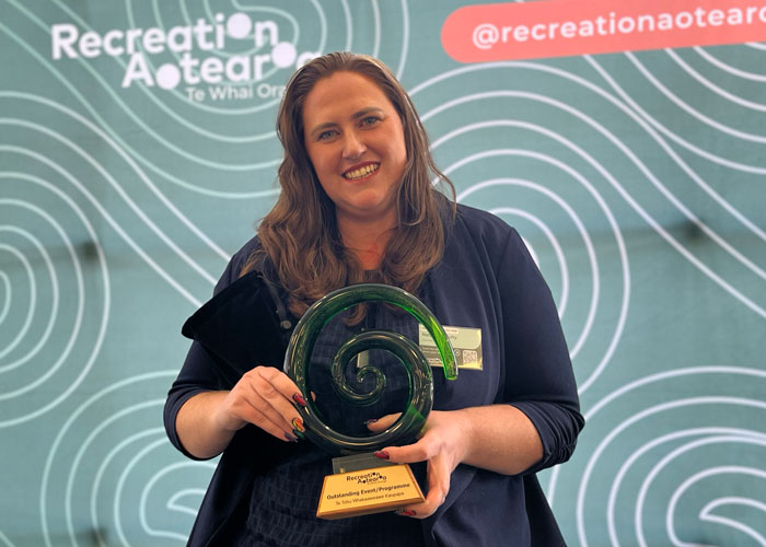 Smiling woman holds a green glass award