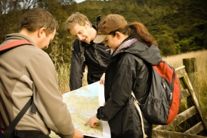 A group of people stand in a field, they are looking at a map