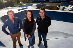 Three people stand on top of a skate park