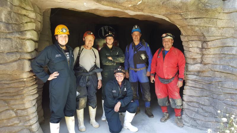 Group standing an cave opening in caving gear