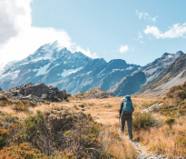 A man walks up a path, which leads to a mountain in the background