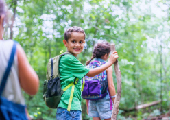 Children hike along a trail, one turns back and smiles at camera