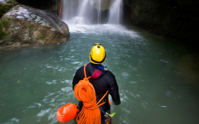 A person stands in front of a waterfall