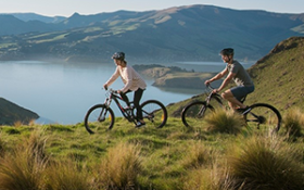 Two people cycle along the port hills of Christchurch