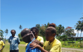 People embracing in front of blue sky and palm trees