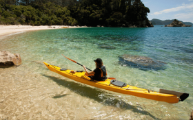 A person kayaks onto the beach
