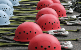 Rows of climbing helmets and ropes are laid out on the ground