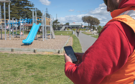 Man standing at a playground making notes into a tablet