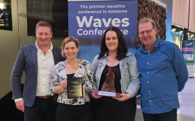 Four people from Hamner Springs stand in front of a sign accepting an award