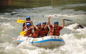 A group of young people are in a raft travelling down a river